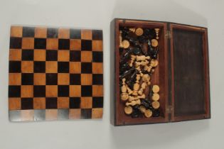 A TRAVELLING CHESS BOX AND FOLDING CHESS BOARD and chess pieces.