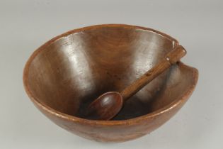 A TREEN CIRCULAR BUTTER BOWL AND SPOON. 13ins diameter.