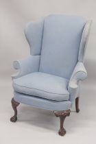 A GEORGE III DESIGN WING ARMCHAIR on carved cabriole front legs with claw and ball feet, upholstered