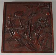 A FINELY CARVED WALNUT PANEL with flowers in relief. 10ins x 10ins.
