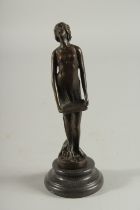 A STANDING BRONZE NUDE on a circular base. 7ins high.