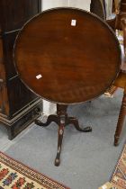 A mahogany circular tilt-top tripod table.