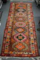 A Persian hall carpet, pink ground with geometric medallions 218cm x 90cm.