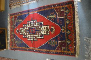 A Persian rug, deep red and rich blue ground with stylised decoration 159cm x 93cm.