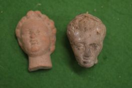 Two early miniature pottery heads, possibly Roman.