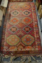 A Persian rug, red ground with stylised decoration, woven tassels to one end 188cm x 100cm.