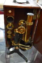 A Swift & Son brass microscope with accessories in a mahogany case.