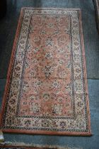 A modern machine made Persian style rug, pink ground with floral decoration 158cm x 80cm.