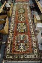 A Persian runner, rust ground with five large central medallions 335cm x 96cm.