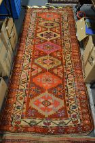 A Persian hall carpet, red ground with geometric motifs 240cm x 100cm.