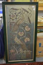 A metal thread and embroidered picture depicting peacocks on a tree.