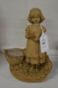 A small pottery group of a young girl with a basket of fruit.