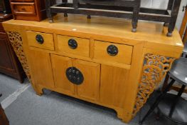 A Chinese light elm sideboard with three drawers and a pair of doors, flanked by carved and