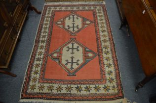 A Persian rug, pink ground with two large central medallions 180cm x 118cm.