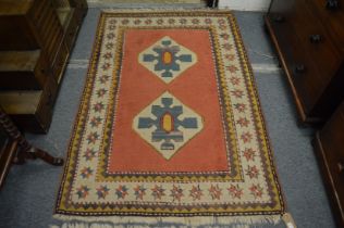 A Persian rug, pink ground with two large central medallions 180cm x 117cm.