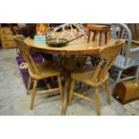 A pine circular table and three chairs.