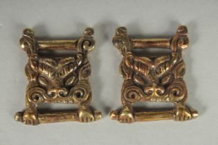 TWO TIBETAN BRONZE LION HEAD ORNAMENTS.