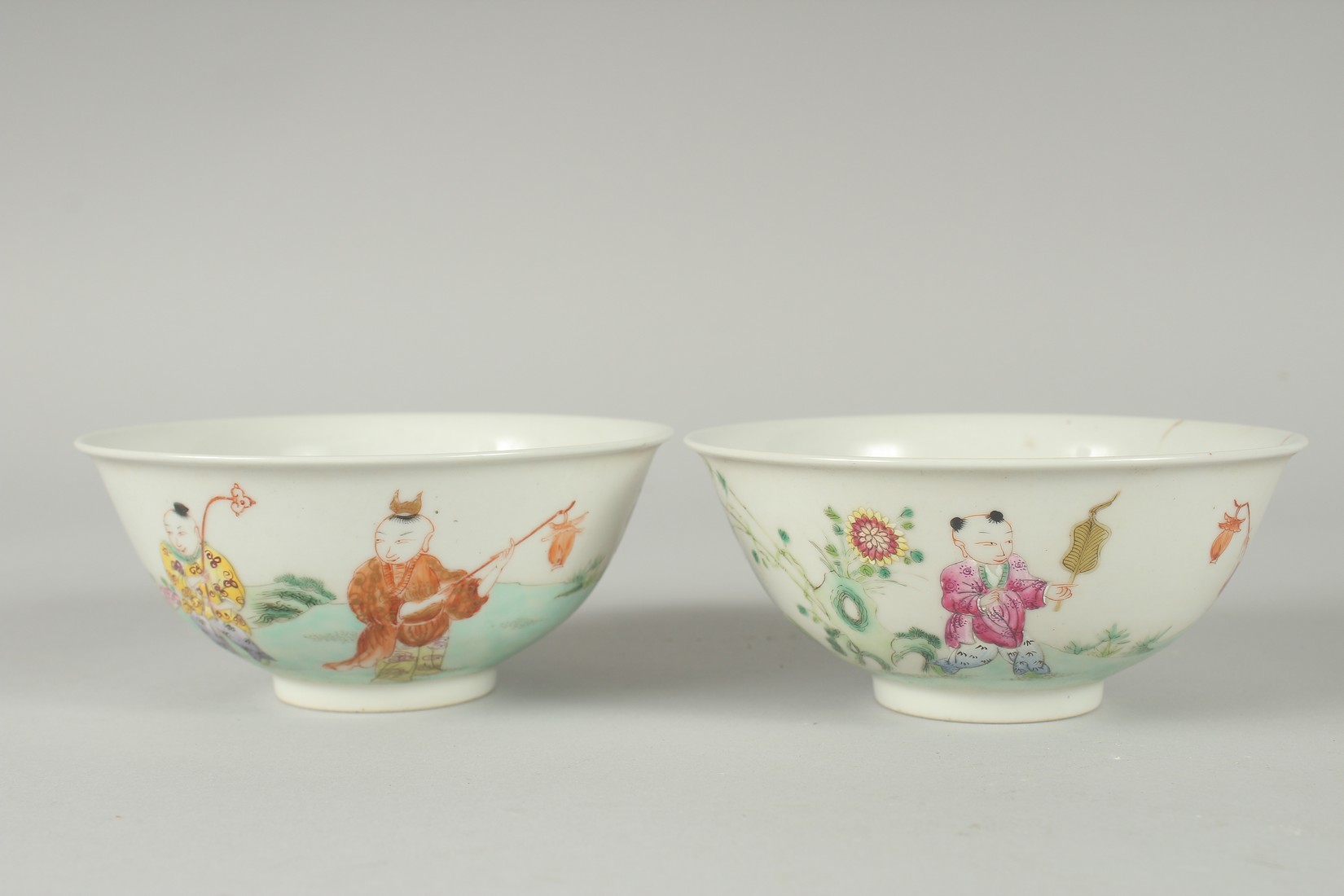 A PAIR OF EARLY 20TH CENTURY FAMILLE ROSE PORCELAIN RICE BOWLS, painted with boys, each with red - Image 2 of 6