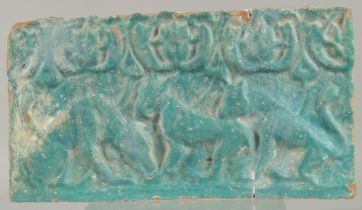 A 12TH CENTURY PERSIAN KASHAN TURQUOISE GLAZED POTTERY TILE, with relief felines. 35.5cm x 19.5cm.