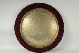 A 19TH CENTURY INDIAN ENGRAVED BRASS TRAY INSET WITHIN A VELVET OVERLAID WOODEN FRAME, beautifully