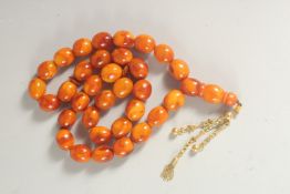 A VERY FINE SET OF AMBER PRAYER BEADS, with gold toggle, each bead approx. 15mm.