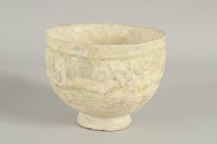 A 11TH-12TH CENTURY ISLAMIC POTTERY FOOTED BOWL, with moulded calligraphy, 15cm diameter.