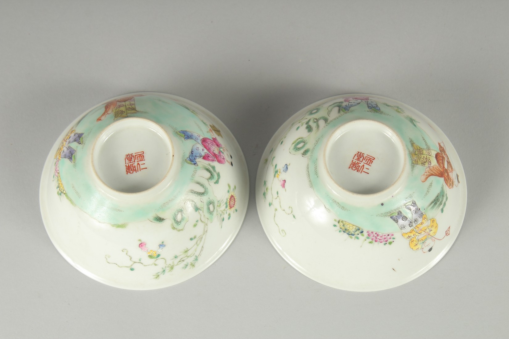 A PAIR OF EARLY 20TH CENTURY FAMILLE ROSE PORCELAIN RICE BOWLS, painted with boys, each with red - Image 6 of 6