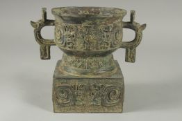A CHINESE ARCHAIC TWO HANDLED BRONZE VASE on a square stand. 7ins high.