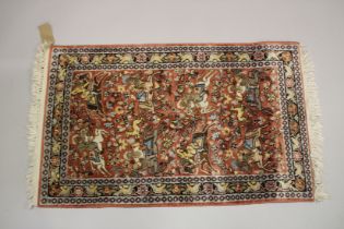 A SMALL PART SILK PERSIAN HUNTING RUG rust ground decorated with huntsmen on horseback. 3ft 3ins x