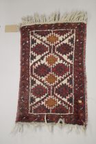 A SMALL PERSIAN MAT red ground with a geometric design. 2ft x 1ft 4ins.