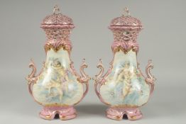 A PAIR OF SEVRES DESIGN PINK GROUND PORCELAIN VASES AND COVERS decorated with cupids. 15ins high.