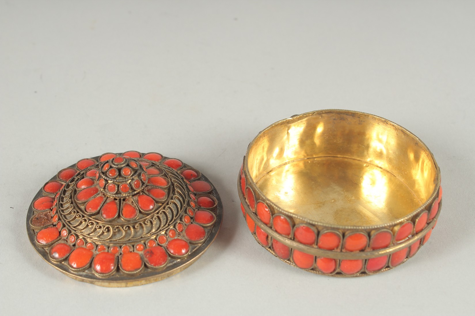 AN INDIAN GILT METAL CIRCUALR BOX AND COVER applied with numerous red enamel inset panels. 3ins - Image 4 of 6