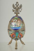 A LARGE RUSSIAN SILVER AND ENAMEL EGG on three curving feet. 12cm long 5cm diameter decorated with