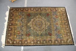 A GOOD PERSIAN SILK CARPET rich green ground with central circular floral medallion decoration all