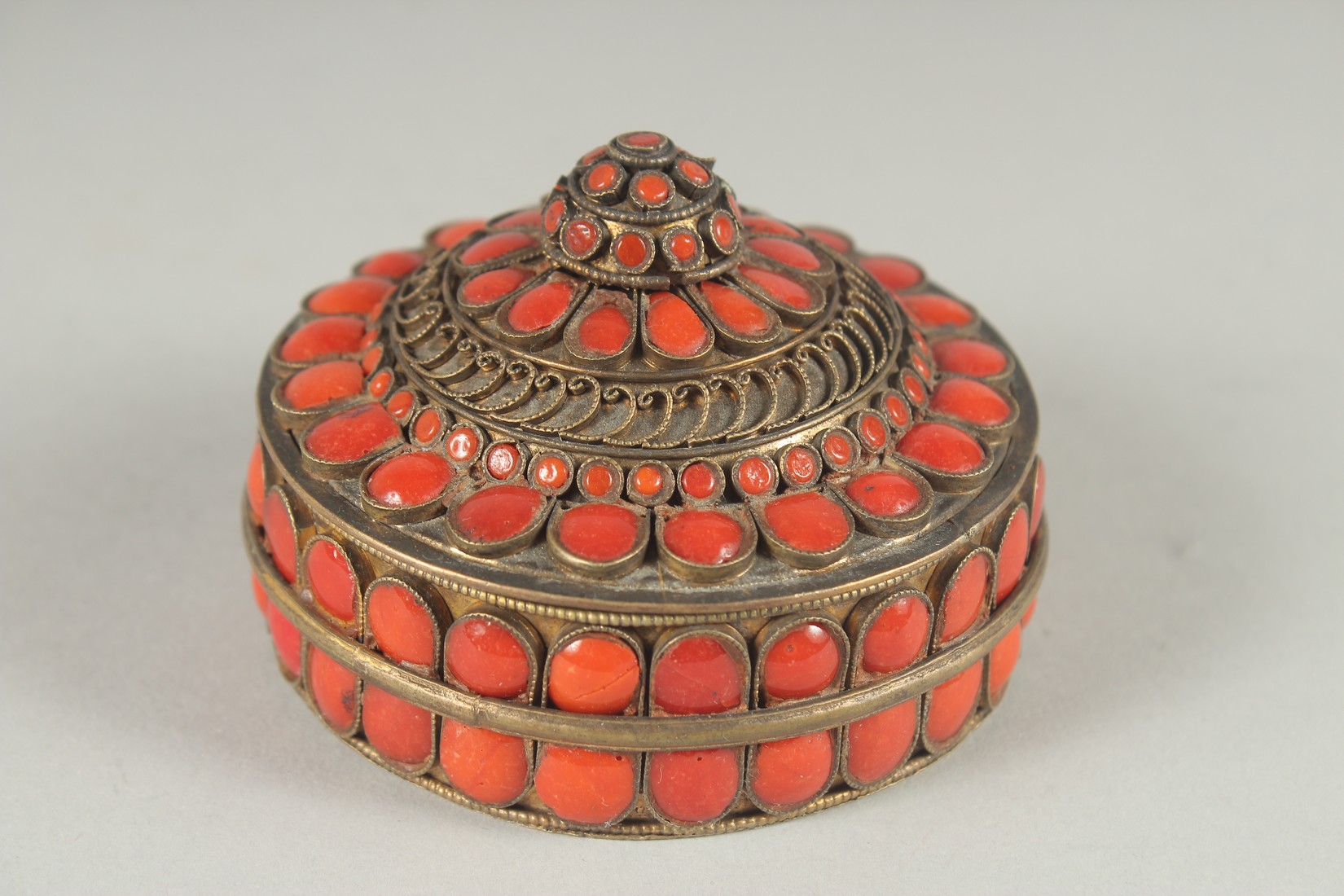 AN INDIAN GILT METAL CIRCUALR BOX AND COVER applied with numerous red enamel inset panels. 3ins - Image 2 of 6