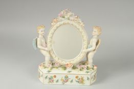 A SEVRES DESIGN PORCELAIN OVAL MIRROR with two cupids and encrusted with flowers. 11ins high.