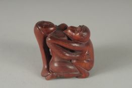 A CARVED WOOD EROTIC NETSUKE, Signed, 2ins.