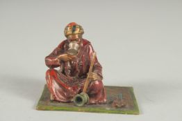 A SMALL AUSTRIAN COLD PAINTED BRONZE OF A MAN sitting on a carpet. 2ins long.