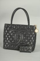 A CHANEL BLACK LEATHER HANDBAG embossed with double C logo on front.