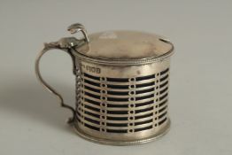 A CIRCULAR PIERCED SILVER MUSTARD POT AND COVER with sapphire blue liner. London 1911.