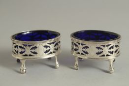 A PAIR OF GEORGE III SILVER OVAL PIERCED SALT CELLARS with bead edge, sapphire blue liners on claw