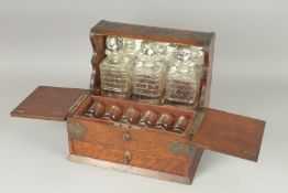 A GOOD VICTORIAN OAK TANTALUS, fitted with three cut glass decanters and stoppers and six glasses