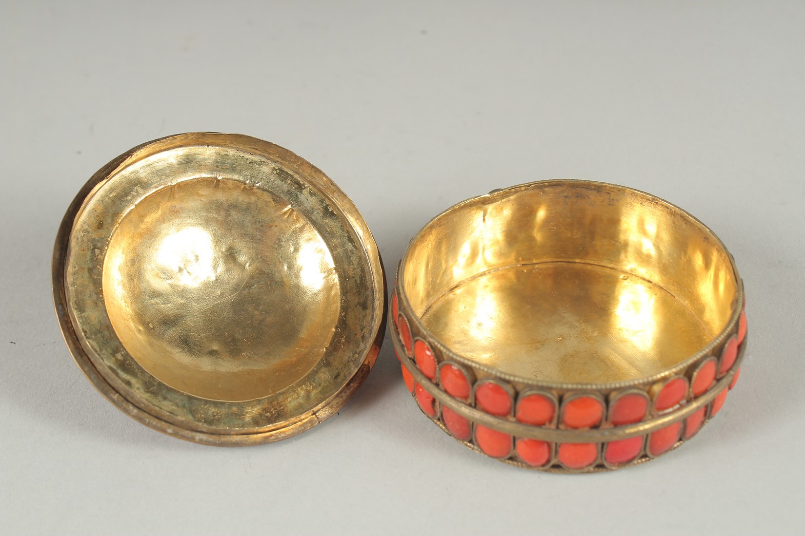 AN INDIAN GILT METAL CIRCUALR BOX AND COVER applied with numerous red enamel inset panels. 3ins - Image 5 of 6