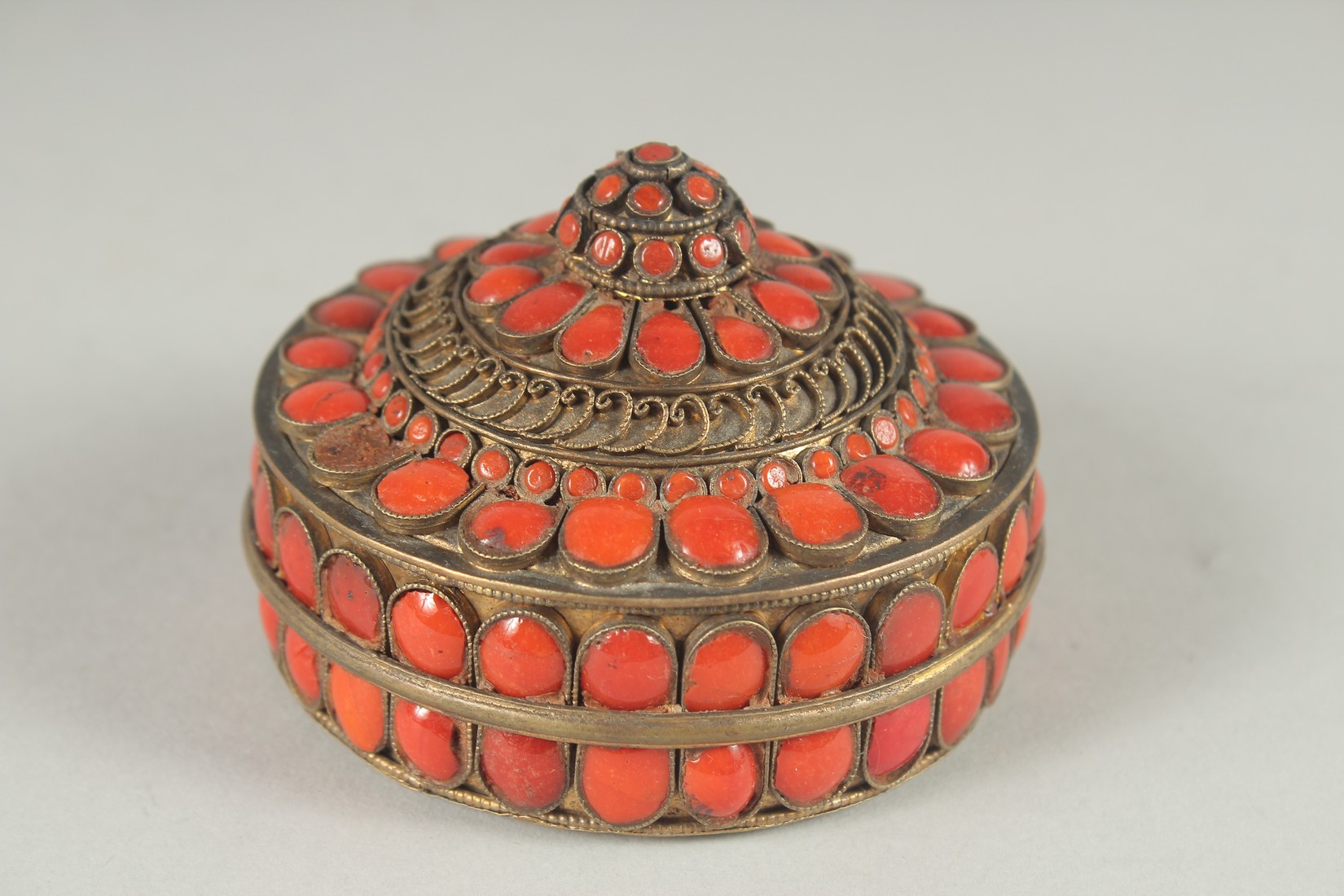 AN INDIAN GILT METAL CIRCUALR BOX AND COVER applied with numerous red enamel inset panels. 3ins - Image 3 of 6