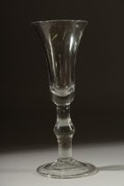 A GEORGIAN GLASS with long tapering plain bowl, knop to the stem. 7ins high.