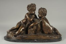 AFTER MOREAU. A GOOD BRONZE OF TWO CUPIDS on a shaped metal base. 19ins long.