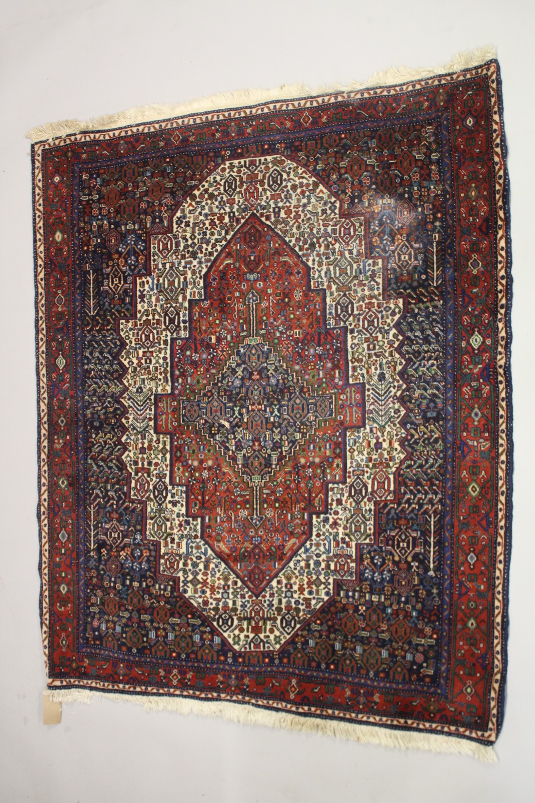 A PERSIAN WOOL CARPET cream, red and blue ground with all over stylised decoration. 4ft 9ins x 4ft