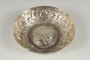 AN EASTERN WHITE METAL CIRCULAR BOWL, with a raised centre, embossed all over with animals