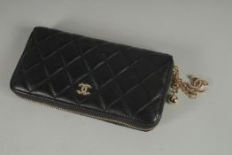 A CHANEL BLACK QUITLED PURSE with gilt double C and ball charms. 8ins long.