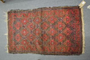 A small Persian rug with stylised decoration 110cm x 65cm.